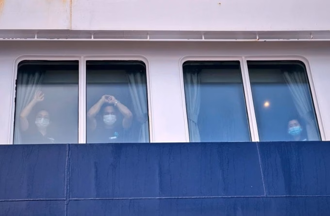Các hành khách theo dõi từ cửa kính khi du thuyền MV Hondius cập cảng Granadilla ở Tenerife, quần đảo Canary, Tây Ban Nha, hôm 10/5. Ảnh: AP